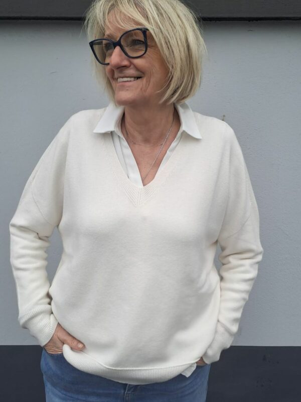 pull à col v poignets et bordure côtelés, manches longues et couleur blanc cassé.